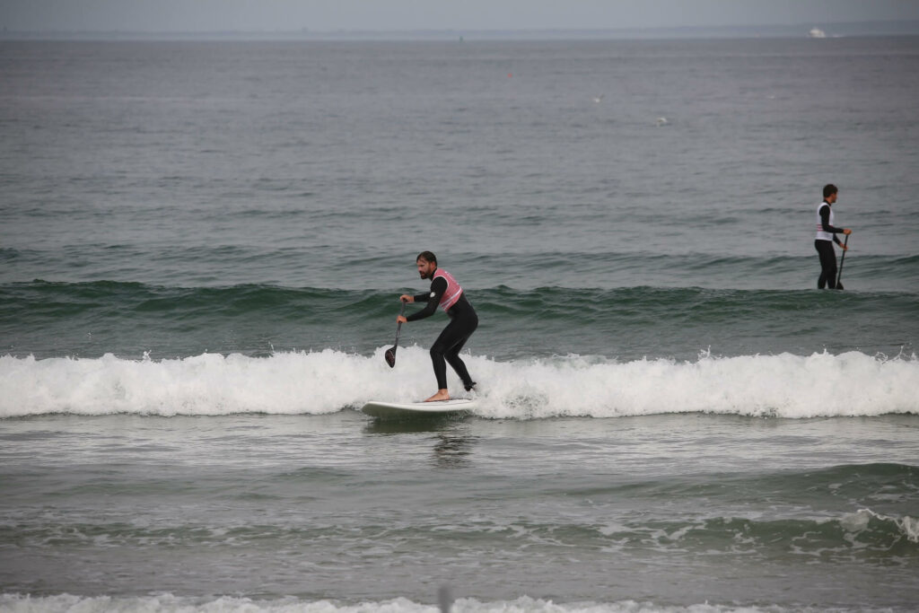 Un surfeur sur une vague avec son Stand Up Paddle