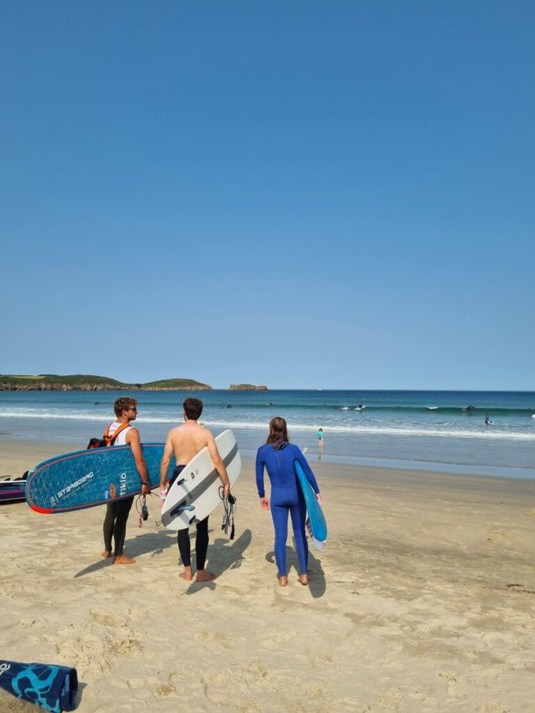 Trois surfeurs qui regardent la mer sur une plage