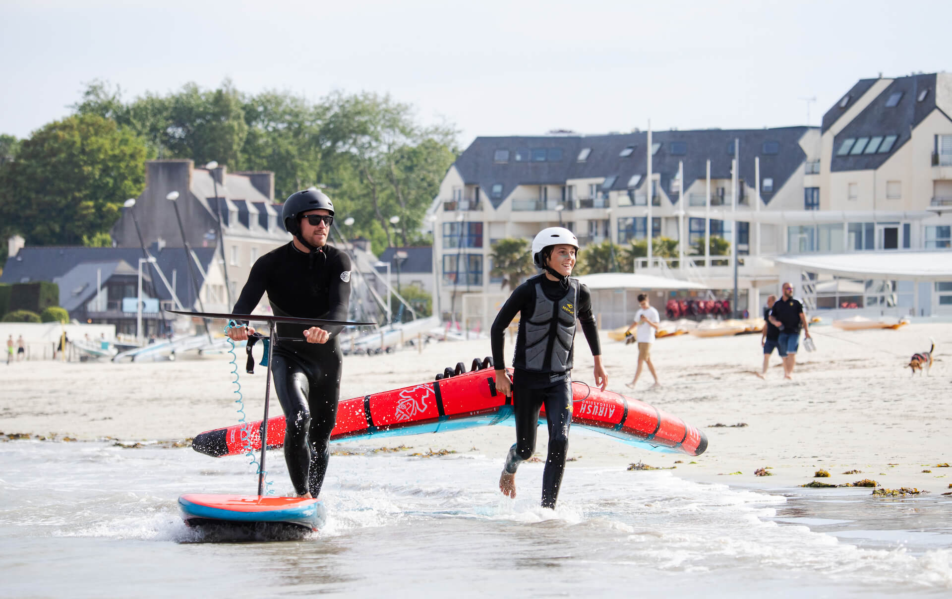 Deux personnes avec une planche de wing foil et une voile